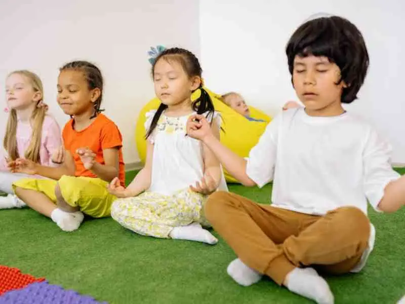 crianças a praticarem yoga em sala de aula